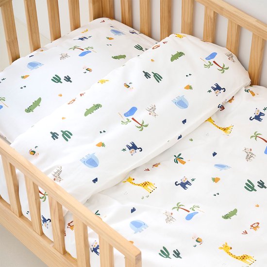 Wit beddengoed met safari dierenprint in een houten ledikant.