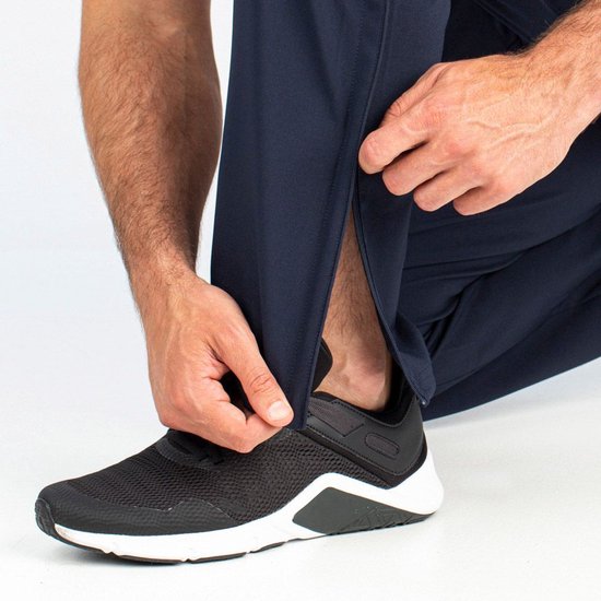 Donkerblauwe sportbroek met ritssluiting aan de onderkant, gedragen met zwarte sportschoenen.