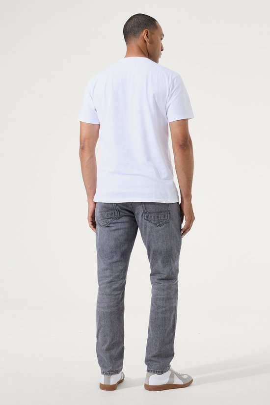 Man, van achteren gezien, draagt een grijze slim fit jeans met een witte t-shirt.