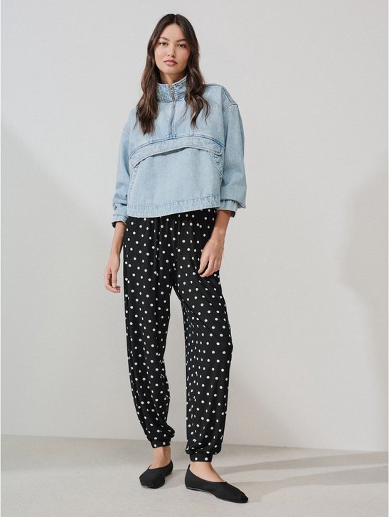 Model in spijkerjack en zwarte joggingsbroek met witte polkadot print