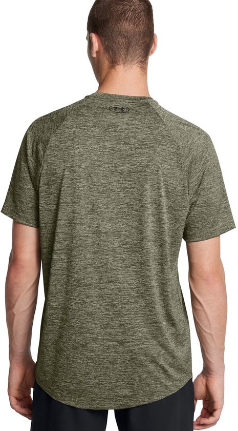 Man draagt een olijfgroen gemêleerd sportshirt van Under Armour met het logo op de rug.