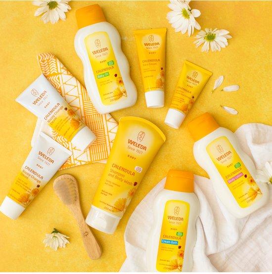 Collectie Weleda babyproducten met calendula, waaronder babyolie, gezichtscrème en bodylotion, op een gele achtergrond.