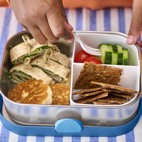 Een kind opent een RVS lunchbox met rolletjes, pannenkoekjes, cherrytomaatjes, komkommer en crackers.