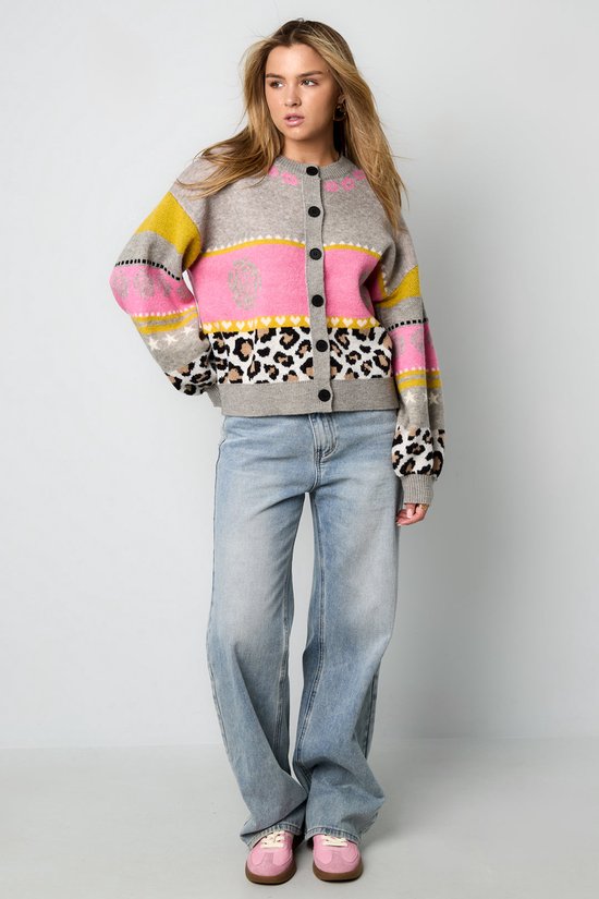 Model draagt grijs vest met roze, gele en zwarte strepen, luipaardprint en bloemenpatronen.