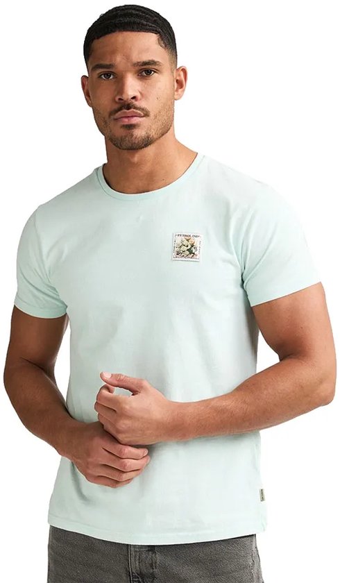 Man in lichtgroen T-shirt met een opgedrukte postzegel met bloemen op de linkerborst.