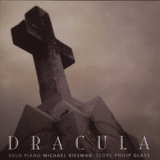 Dichtbij opname van een stenen kruis op een graf, met de titel DRACULA onderaan.