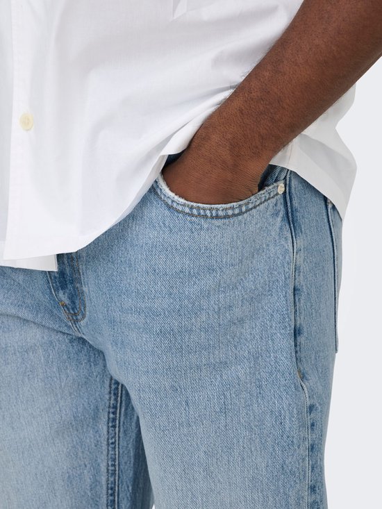 Detail van een man met witte korte mouwen blouse en lichtblauwe jeans, hand in broekzak.