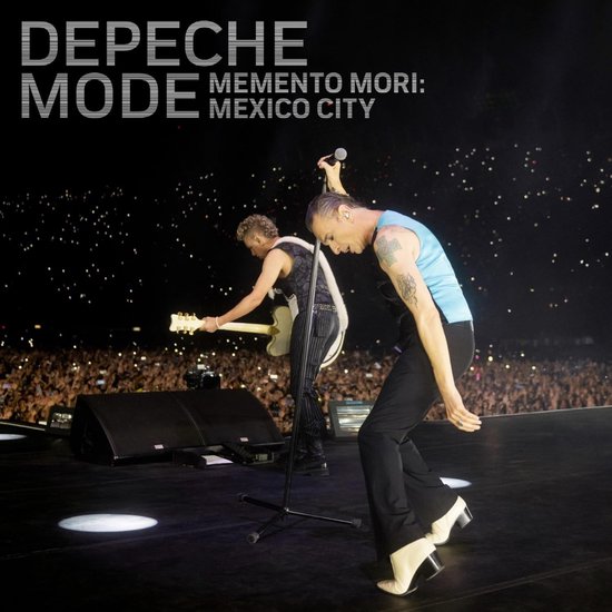 Depeche Mode live, zanger Dave Gahan in blauw vest, Martin Gore op gitaar, voor een publiek met lichtjes.
