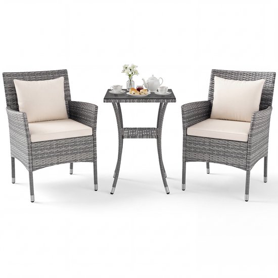 Chaises en rotin gris avec coussins beiges et une table avec plateau en verre, isolées sur fond blanc.