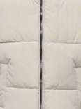 Lichtbeige pufferjack met verticale rits en horizontale stiksels.