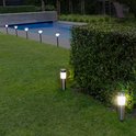 Tuinverlichting met vier RVS solar lampen langs een zwembad en met twee van dezelfde lampen op de voorgrond.