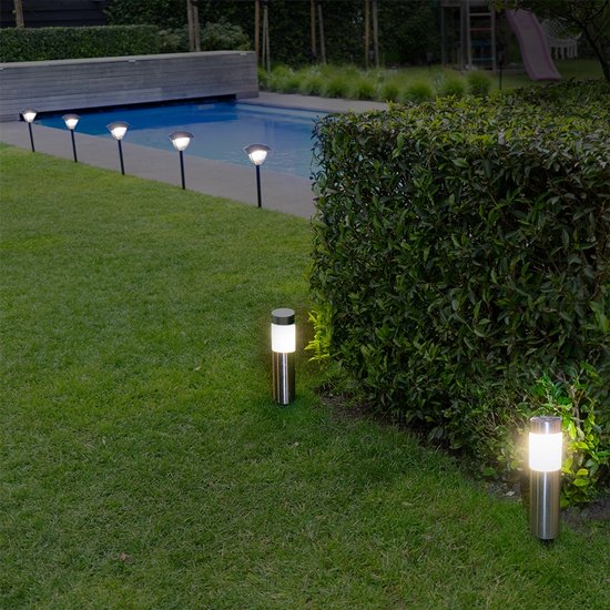 Tuinverlichting met vier RVS solar lampen langs een zwembad en met twee van dezelfde lampen op de voorgrond.