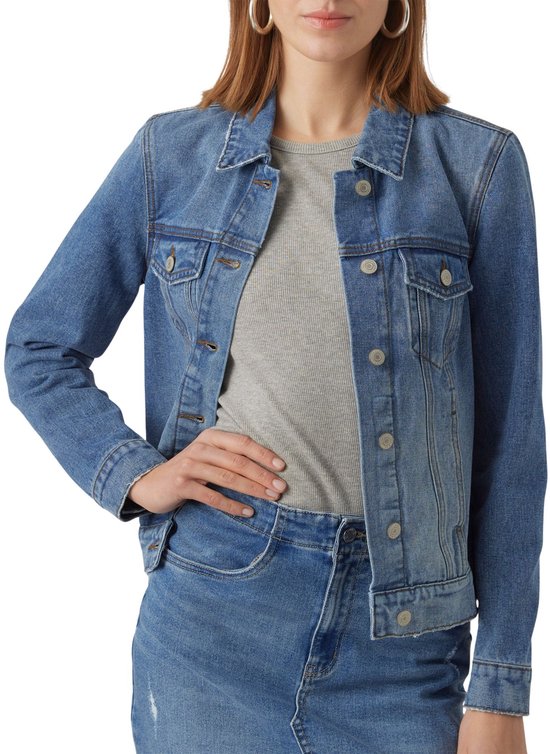 Gros plan sur un modèle portant une veste en jean bleue, main sur la hanche.
