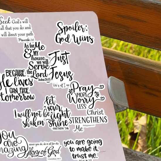 Zwart-witte religieuze stickers op een notitieboekpagina, met teksten zoals 'Spoiler: God Wins'.