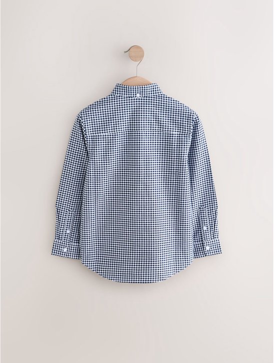 Achterkant van een blauw met wit vichy ruitpatroon overhemd met lange mouwen, hangend aan een haakje.