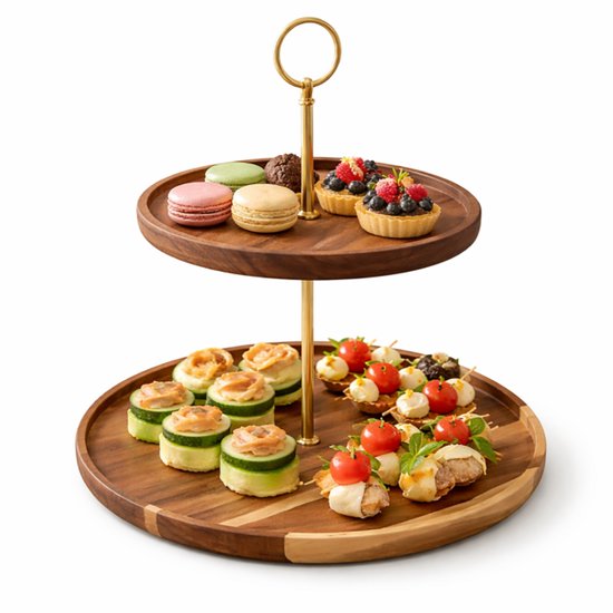 Tweelaags etagère van donker hout met gouden handvat. Bovenop macarons en taartjes, onderop rolletjes komkommer en spiesjes. Studio-opname.