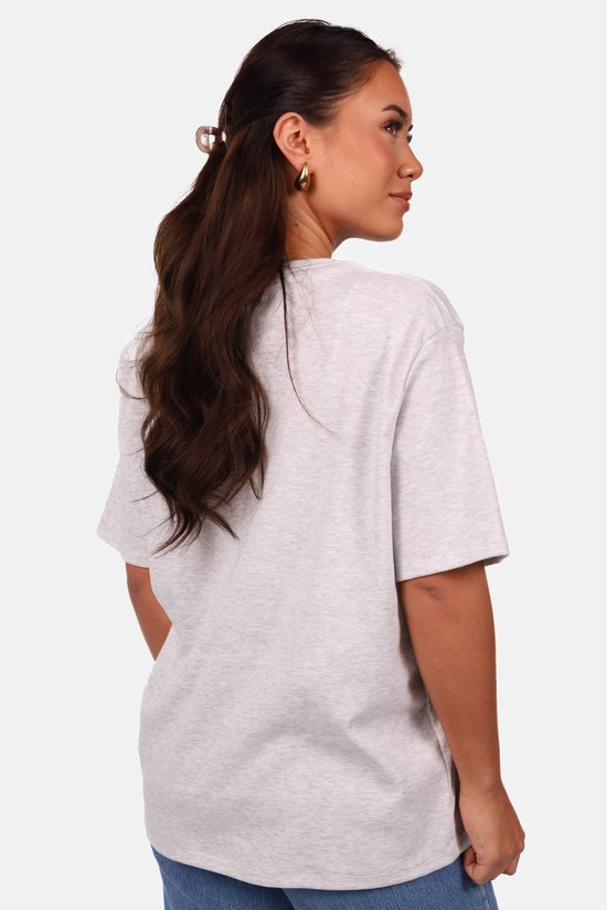 Achterkant van een model in een lichtgrijs, oversized T-shirt met korte mouwen.