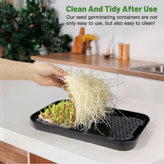 Hand haalt wortels uit een zwarte kiemschaal met rode microgreens. Makkelijk schoon te maken.