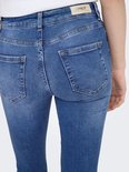 Close-up van de achterkant van blauwe skinny jeans met distressed details en zakken.