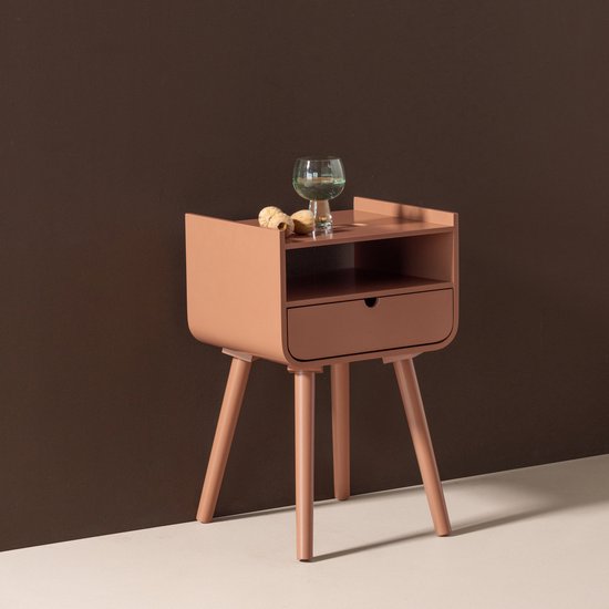 Oudroze bijzettafel met open vak en lade, op schuine pootjes, met glas en decoratie.