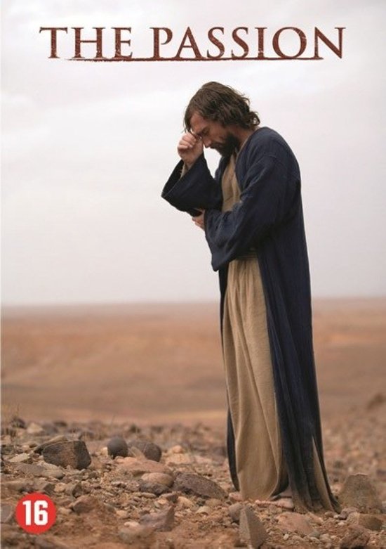 Een man met een baard, gekleed in een donkerblauwe mantel en beige tuniek, staat in een dorre, rotsachtige omgeving. Boven de afbeelding staat "THE PASSION".