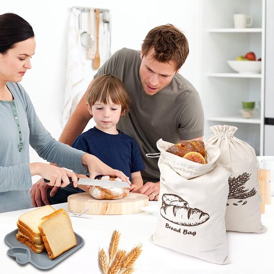 Familie in een keuken, een jongen snijdt brood. Twee off-white canvas zakken met brood- en korenarenprint.