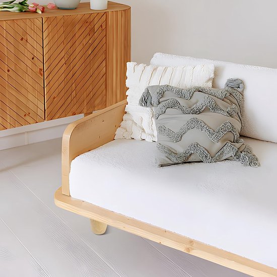 Een deel van een witte sofa met houten frame en een houten poot, versierd met grijze en witte kussens.