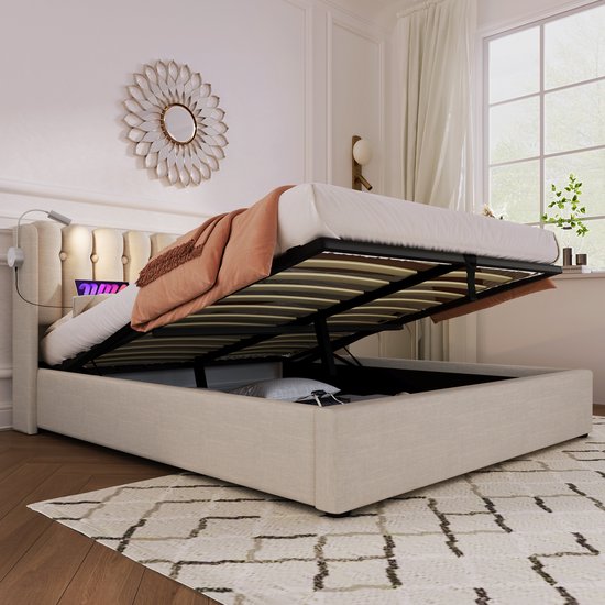 Beige gestoffeerd eenpersoonsbed met opklapbare lattenbodem en zicht op de opbergruimte.