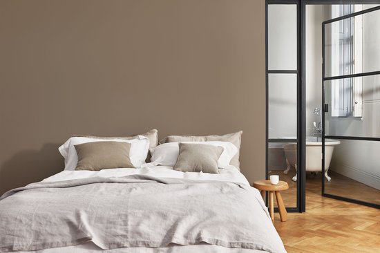 Slaapkamer met een tweepersoonsbed, bruine muur en een open badkamer.