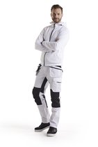 Model draagt een witte Blåkläder werkbroek en wit vest met armen over elkaar.