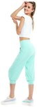 Model in mintgroene capribroek met wijde pijpen, witte crop top en sneakers.