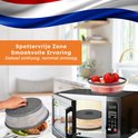 Un couvercle de micro-ondes gris pliable sur un micro-ondes, avec un bol de tomates au-dessus et une main plaçant un couvercle sur une assiette de poulet et de légumes.