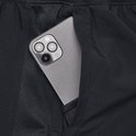 Close-up van een smartphone in de zak van een zwarte sportbroek met mesh-detail.