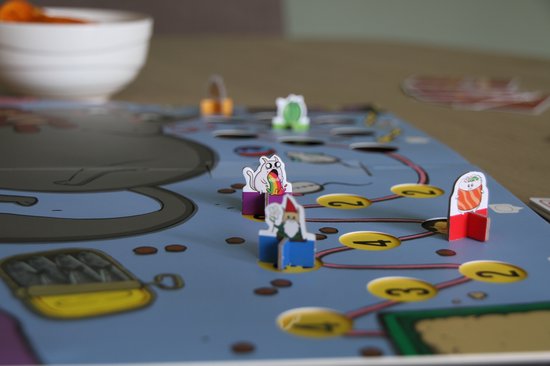 Een close-up van het Exploding Kittens bordspel met speelfiguren van een kat, een gnome en een lama in een cartoonstijl.