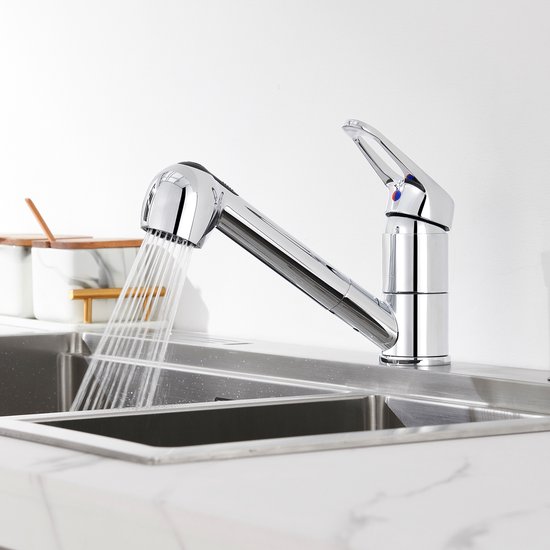 Robinet de cuisine argenté avec douchette extractible, projetant de l'eau dans un évier double.