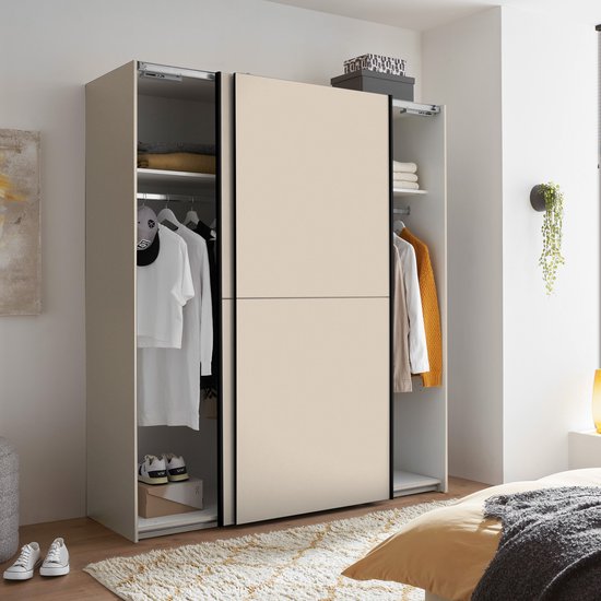 Halfopen beige kledingkast, met kleding aan de linkerkant, in een slaapkamer.