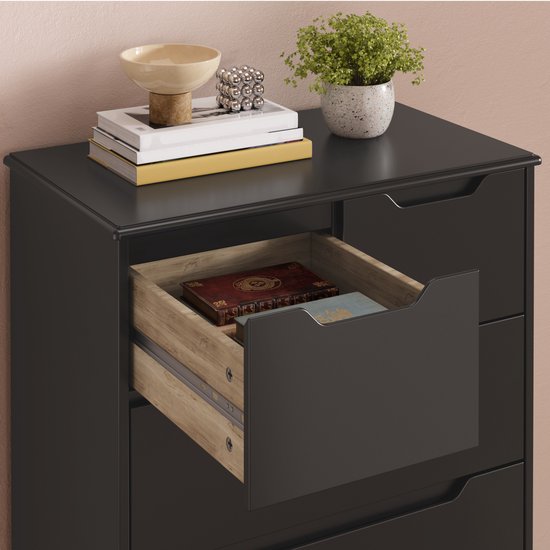 Commode noire avec un tiroir ouvert, des livres et des décorations sur le dessus.