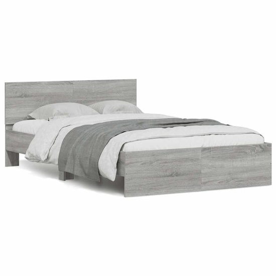 Opgemaakt grijs bedframe met hoofdeinde, zonder verlichting, met witte en grijze dekens.