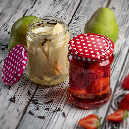 Twee glazen weckpotten, één met peren, de andere met rode vruchten. Deksel met roze stippen.