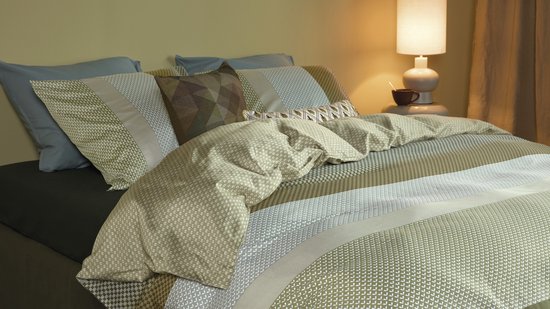 Lit fait avec une housse de couette verte à rayures et des coussins à motif géométrique.