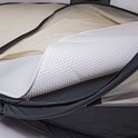 Het geperforeerde, witte matraskussen wordt uitgevouwen op het off-white babymatras in de donkergrijze hoes.