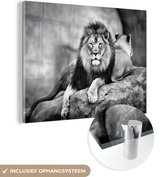 MuchoWow® Glasschilderij 160x120 cm - Schilderij acrylglas - Leeuw en een leeuwin liggend op een rots - zwart wit - Foto op glas - Schilderijen