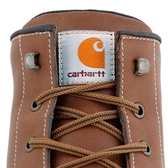 Close-up van de tong van een bruine Carhartt werklaars met het oranje Carhartt logo.