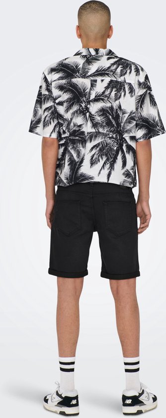 Man met palmbomenprint shirt en zwarte shorts, gezien van achteren.