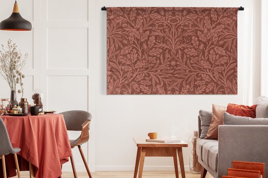 Wandkleed met bruin bloem- en bladerpatroon in een sfeervolle woonkamer boven een bank.