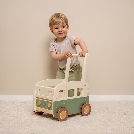 Lachend jongetje duwt een groene en beige houten loopwagen met ronde wielen.
