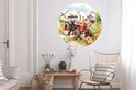 Een ronde muurcirkel met een rode tractor en veel boerderijdieren, in een woonkamer met een stoel en bijzettafel.