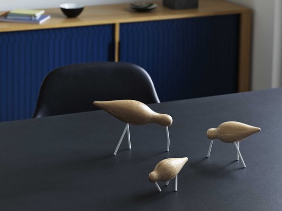 Drie houten vogeldecoraties met witte, metalen pootjes op een zwarte tafel.