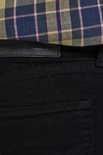 Sluiting van zwarte jeans met label 'CRAFTSMANSHIP AND DEDICATION'.