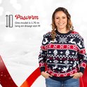 Vrouw draagt een kersttrui met rendieren, sneeuwvlokken en kerstbomen. Ons model is 1.70m en draagt maat M.